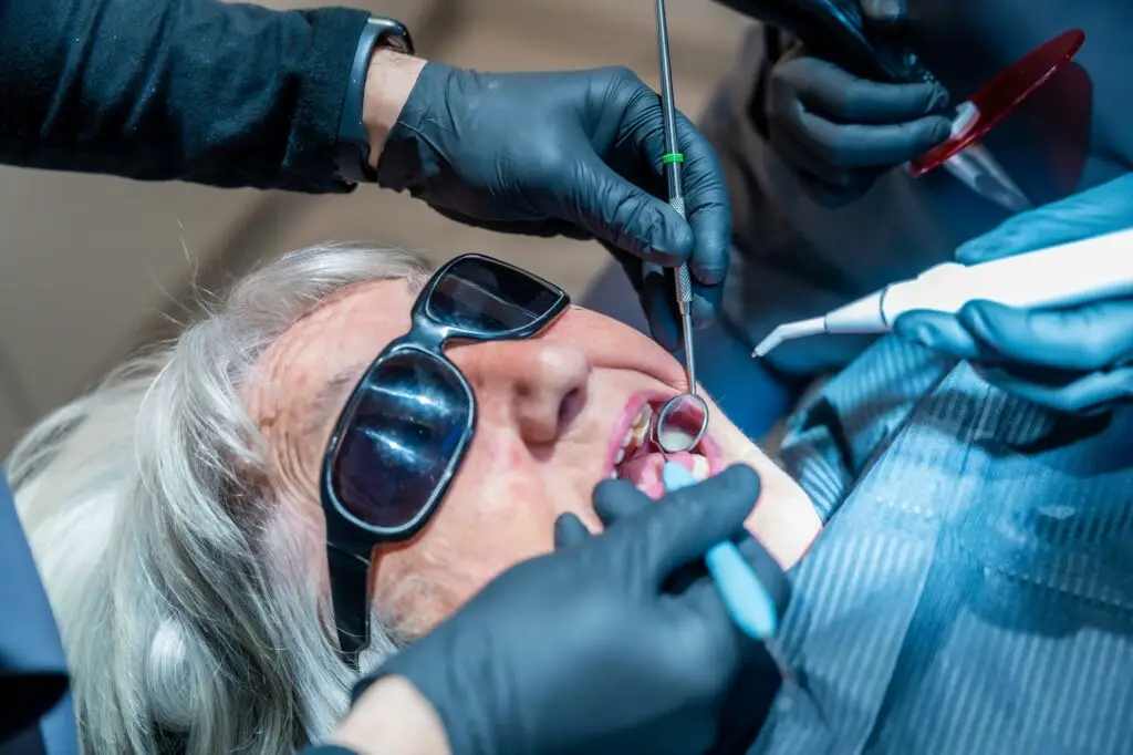 Dentists performing dental procedure on senior woman