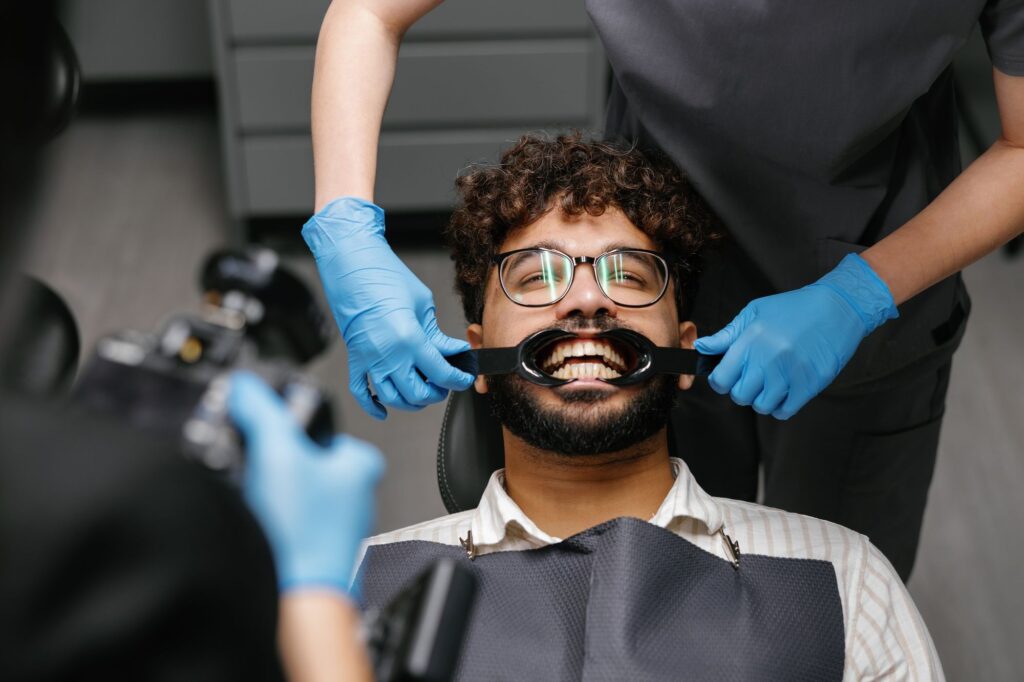 Dentist examining patient's teeth with dental retractor